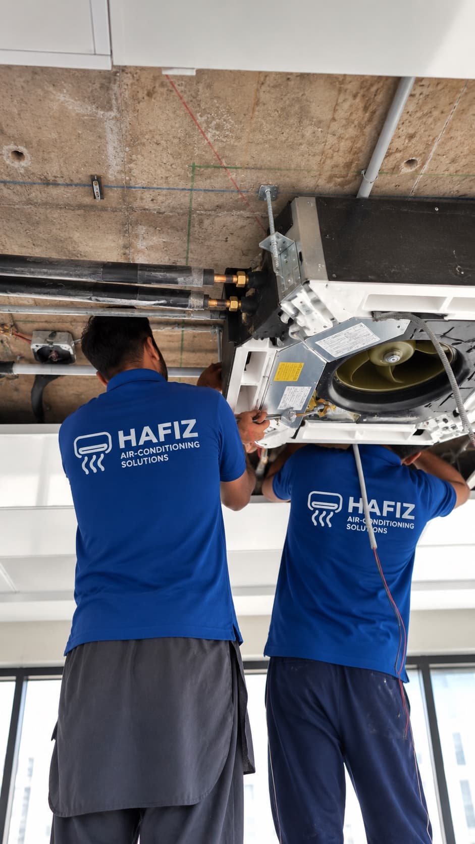 Technicians lifting a ceiling cassette into place at Evacuee Trust Complex