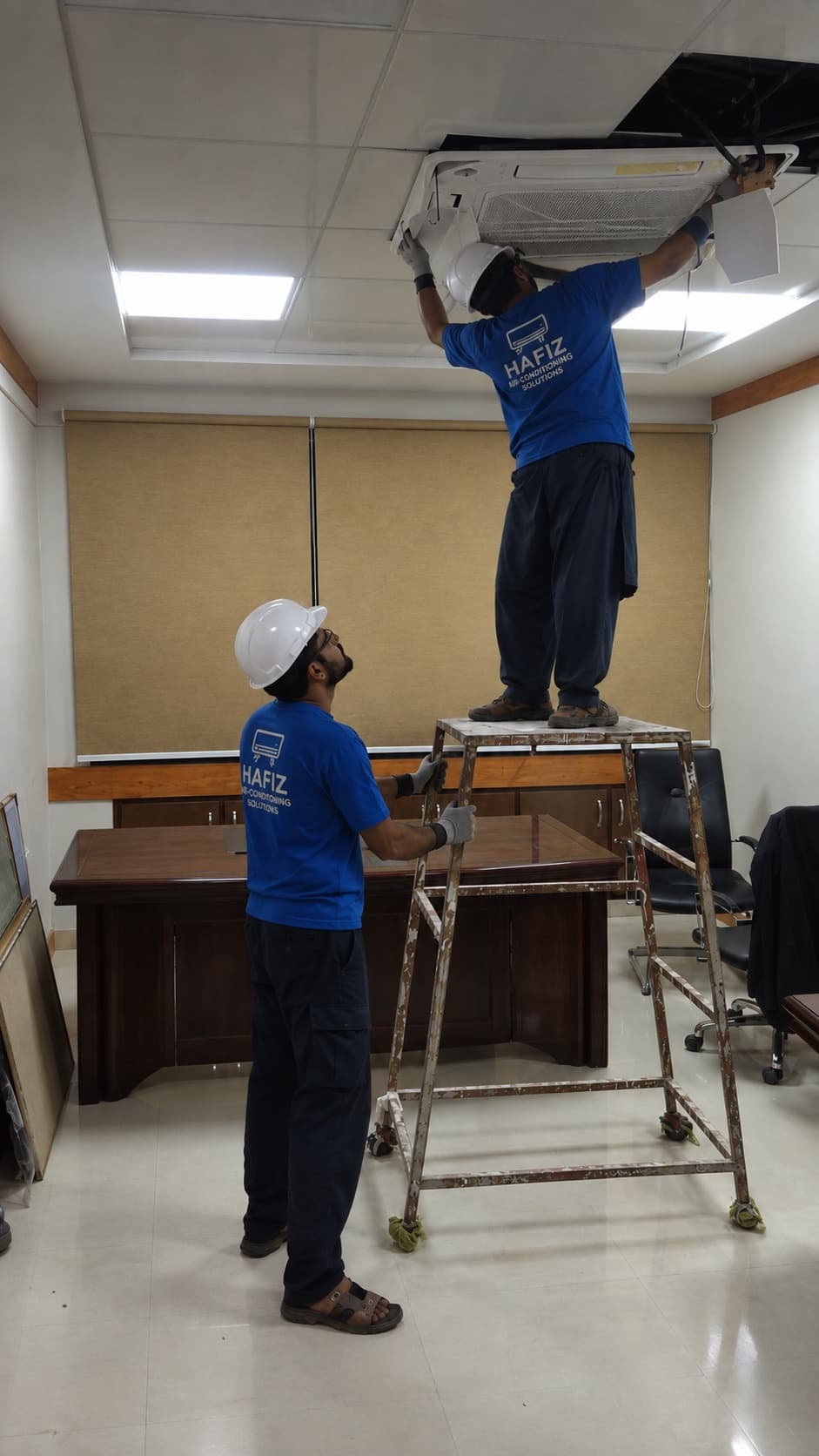 Technicians installing a ceiling indoor unit in an office at the National Police Academy