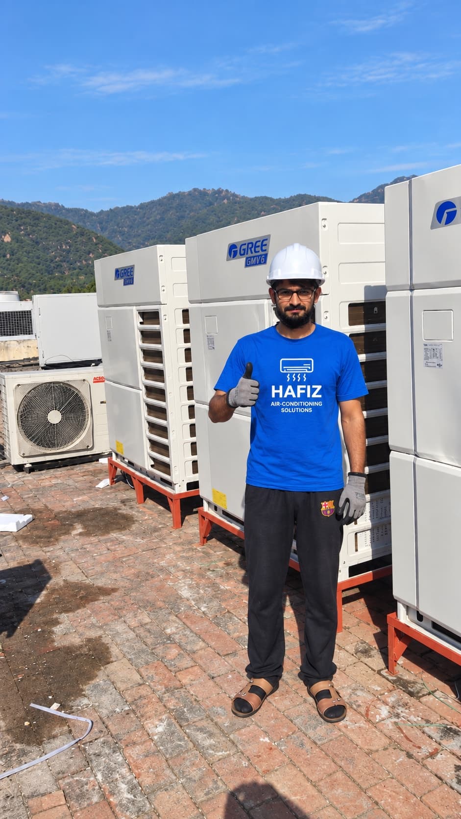 Site engineer beside Gree VRF outdoor units on the rooftop at the National Police Academy