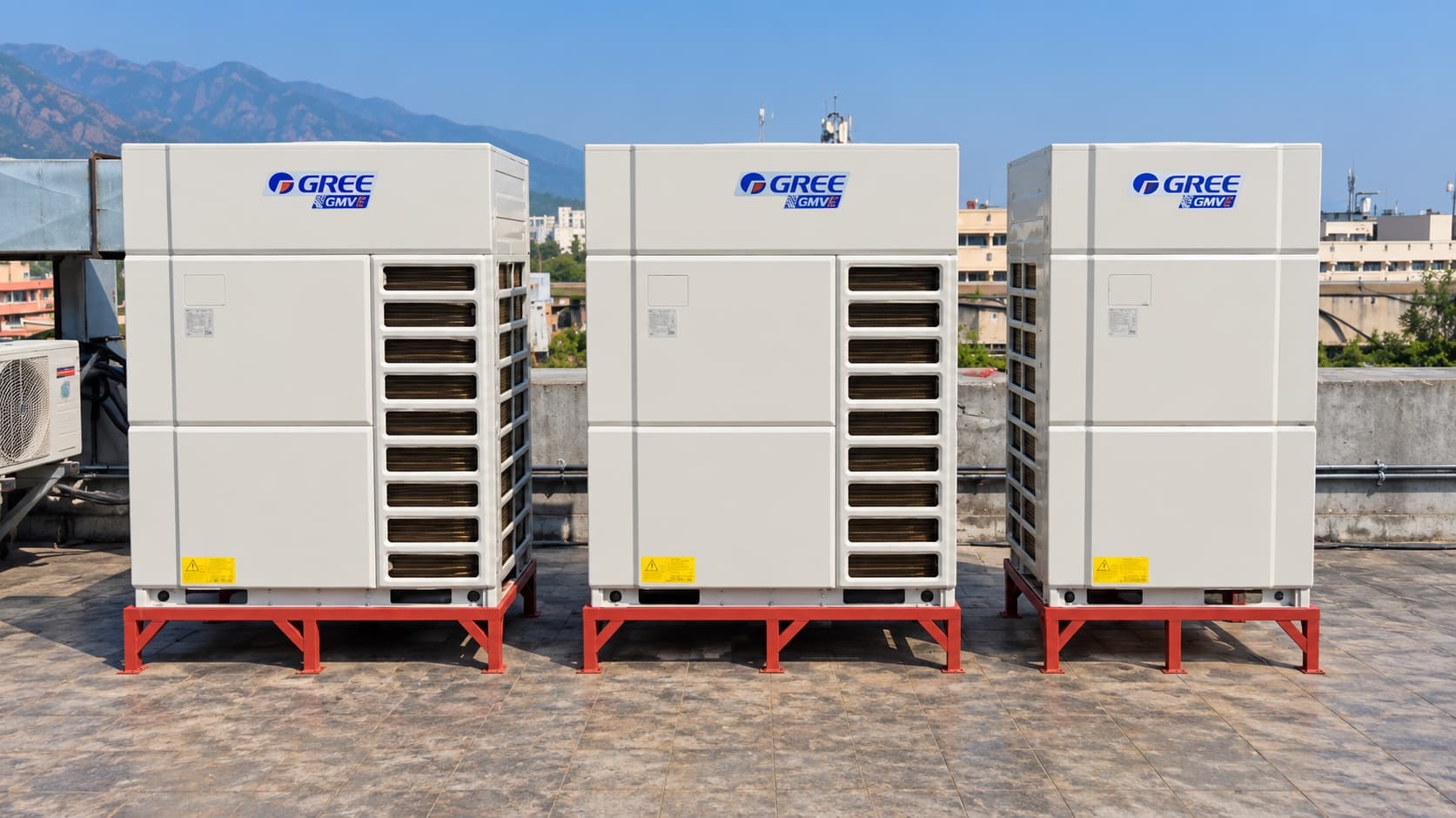 Three Gree VRF outdoor units on red steel stands on the rooftop at Evacuee Trust Complex, Islamabad