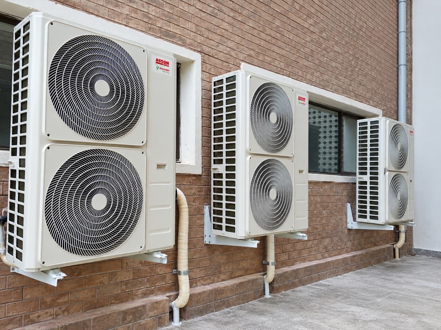 Large outdoor condensing units wall-mounted on brackets at Kohat Institute of Medical Sciences