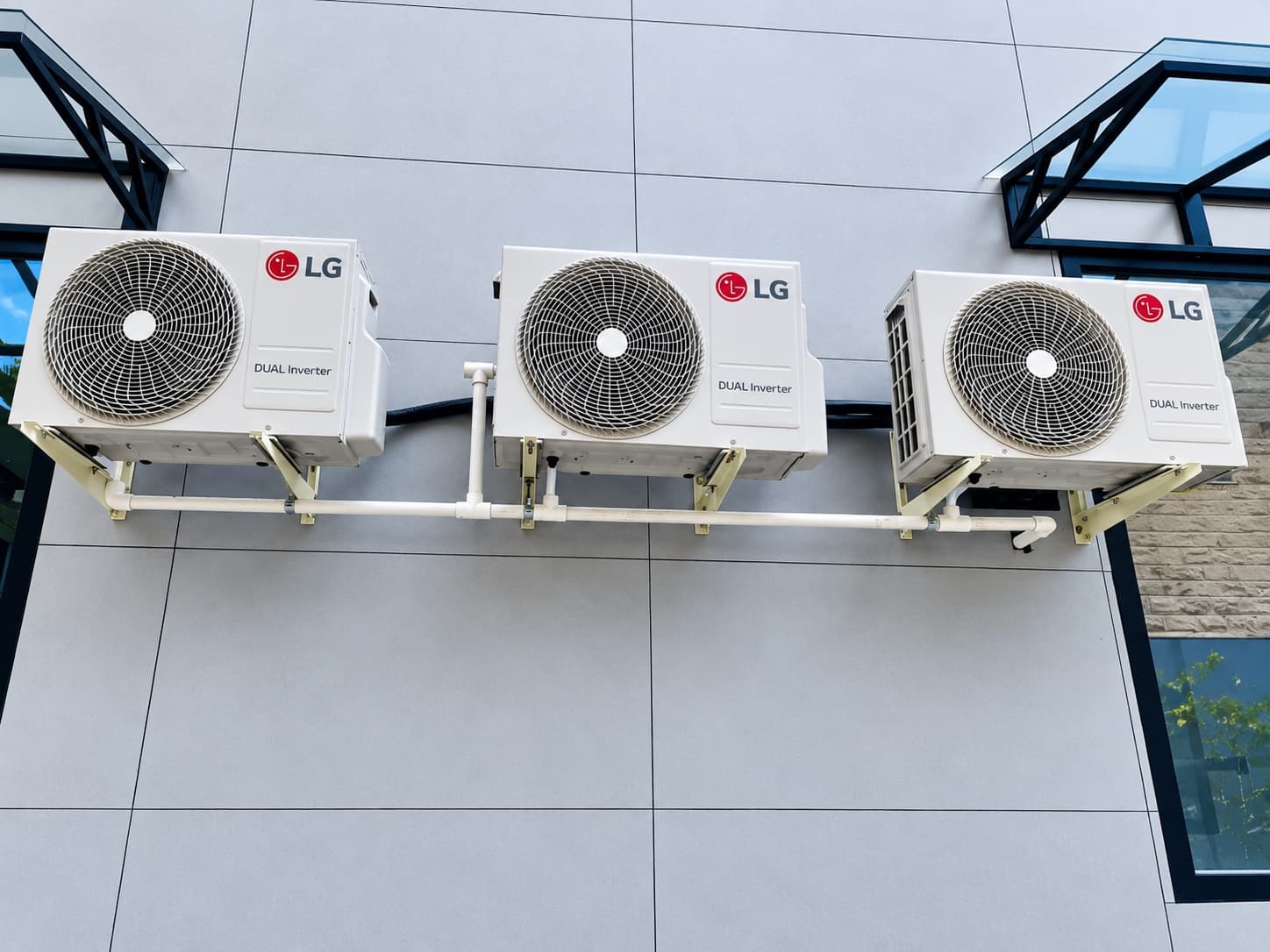 Three LG Dual Inverter outdoor units with trunked piping on a residential wall